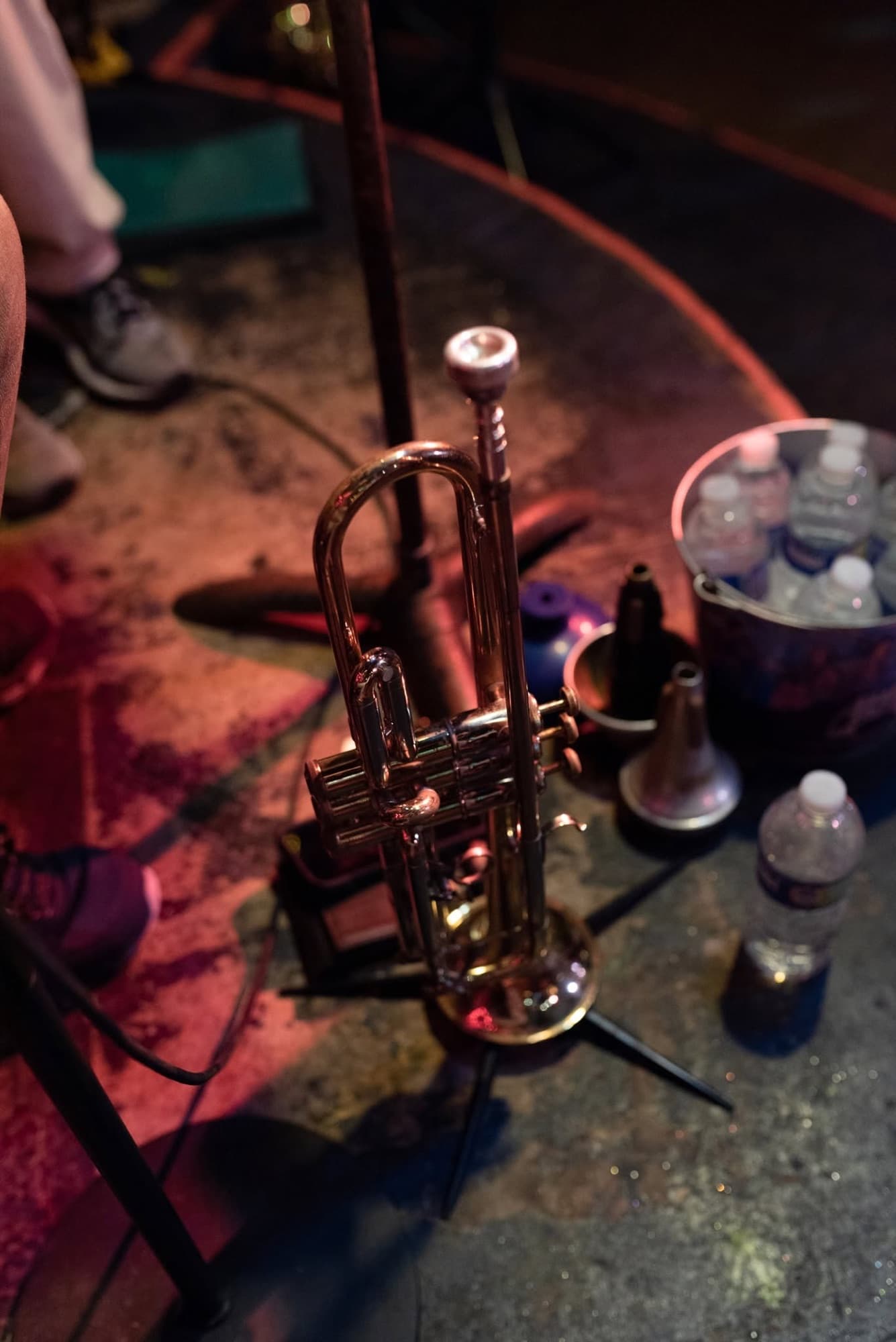 A trumpet resting backstage beside mutes and water bottles