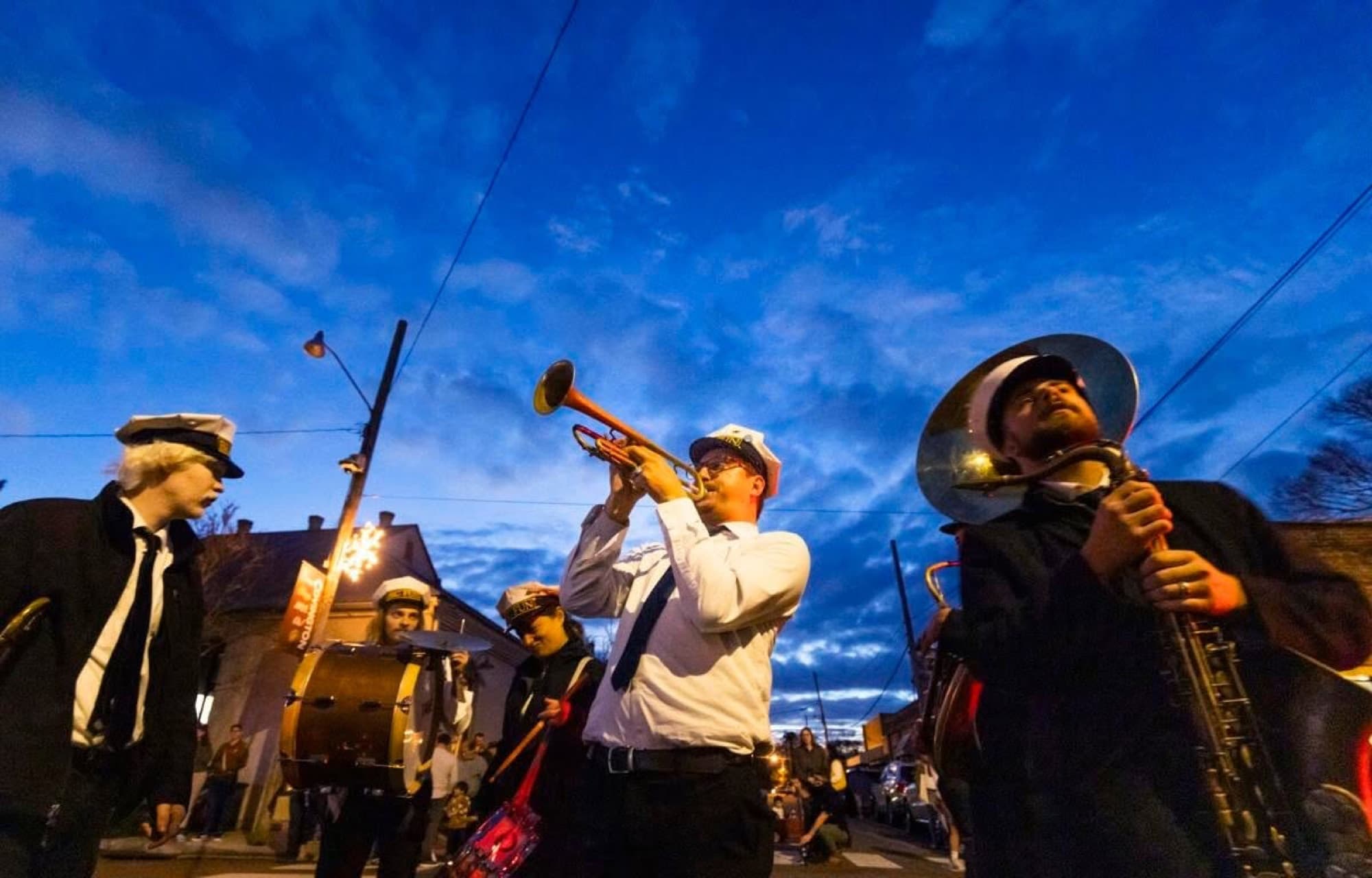 Reid Poole playing trumpet with a brass band at blue hour